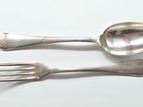 two spoons and a fork on a white table