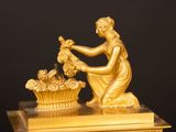 a gold statue of a woman with a basket of flowers on top of a table