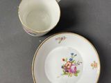 two cups and saucers with floral designs on them on a table
