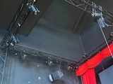 a stage with a red curtain and spotlights on the ceiling