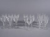twelve crystal wine glasses lined up in a row on a white surface