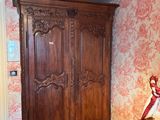 a wooden armoire in a bedroom with a red and white wallpaper