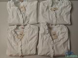 quatre paires de pyjamas blancs posées sur une table blanche