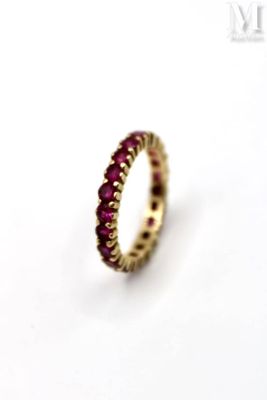 a close up of a ring with red stones on a white surface