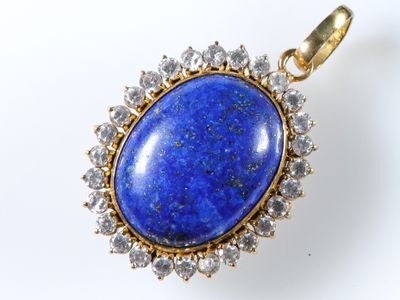 un gros plan d'un pendentif orné d'une pierre bleue entourée de diamants