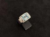 an image of a ring with a blue topaz stone on a black surface