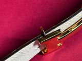 a white belt with a gold buckle on a pink surface