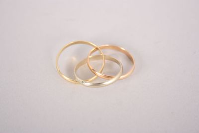 two gold wedding rings sitting on top of each other on a white surface