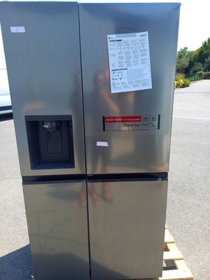 un réfrigérateur argenté posé sur une palette dans un parking
