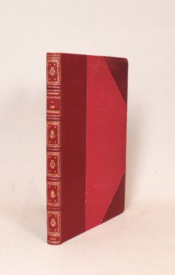 un vieux livre à la couverture rouge posé sur une surface blanche