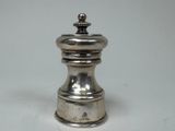 une poivrière en argent posée sur une table blanche