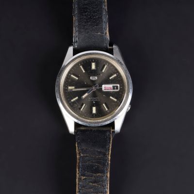 a close up of a watch on a black surface with a black background