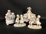 three white figurines of people sitting on a bench
