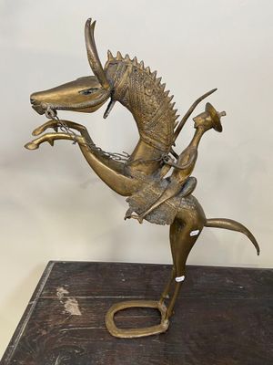 statue en bronze représentant un cheval avec un cavalier sur le dos, posée sur un socle en bois