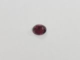 a close up of a red garnet stone on a white surface