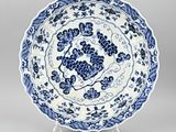 a blue and white plate with grapes on it