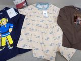 three children ' s pajamas and a shirt on a couch