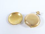 a gold pocket watch and a gold pocket watch on a white surface