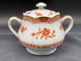 a white and orange teapot with a gold rim