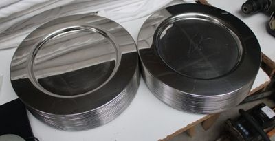two silver plates sitting on a table with a camera next to them