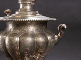an antique silver vase with a lid and handles on a stand