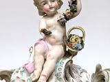 a figurine of a cupid sitting on top of a vase