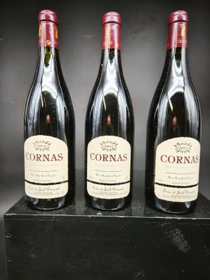 trois bouteilles de vin rouge sont posées sur une boîte noire