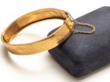 une bague en or munie d'une chaîne, posée sur un coffret noir