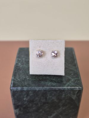 a pair of diamond stud earrings sitting on top of a marble block