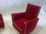 pair of red chairs with white piping on the arms and legs