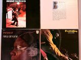 quatre albums de styles musicaux variés sont posés sur une surface blanche