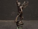 statue of an angel with a broom on a pedestal on a black background
