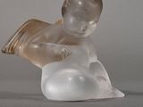une figurine en verre représentant un bébé assis sur un nuage