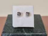 a pair of diamond stud earrings sitting on top of a marble block