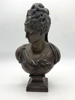 a bronze bust of a woman wearing a headdress on a wooden base