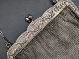 an antique silver metal mesh purse with a chain strap and clasp