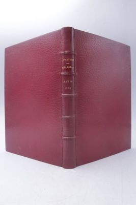 an old book with a red cover sitting on top of a white surface