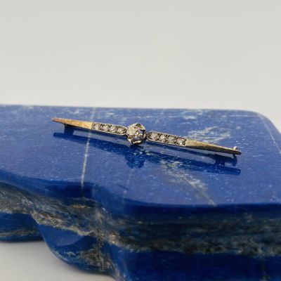 an image of a diamond bar broochle on a blue marble slab