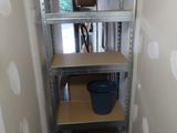 a small room with shelves and a bucket on the floor