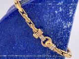 une photo en gros plan d'un bracelet en or posé sur un vase bleu