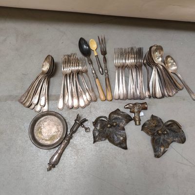 a lot of silverware on the floor next to a bowl and spoon