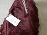 burgundy fringed bag with a tag on it sitting on a bed