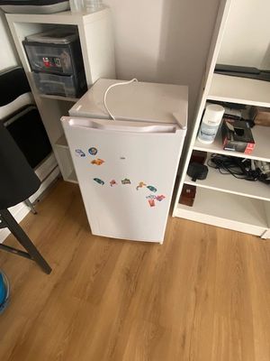 un petit réfrigérateur blanc dans le coin d'une pièce