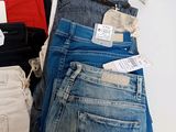several pairs of jeans are stacked on a table with tags on them
