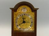 une horloge en bois avec un cadran doré sur fond blanc