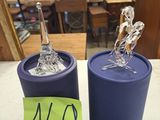 two blue containers with silver figurines on top of them