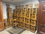 de nombreuses chaises en bois empilées les unes sur les autres dans une pièce