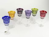 several different colored wine glasses are lined up on a white surface