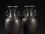 une paire de vases en bronze sur un socle, sur fond noir