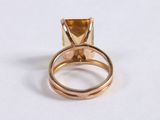 gold ring with citrine stone on top of it on a white surface